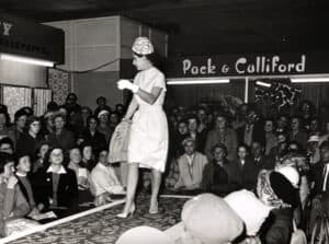 On the catwalk modelling a full outfit with dress, coat and hat
